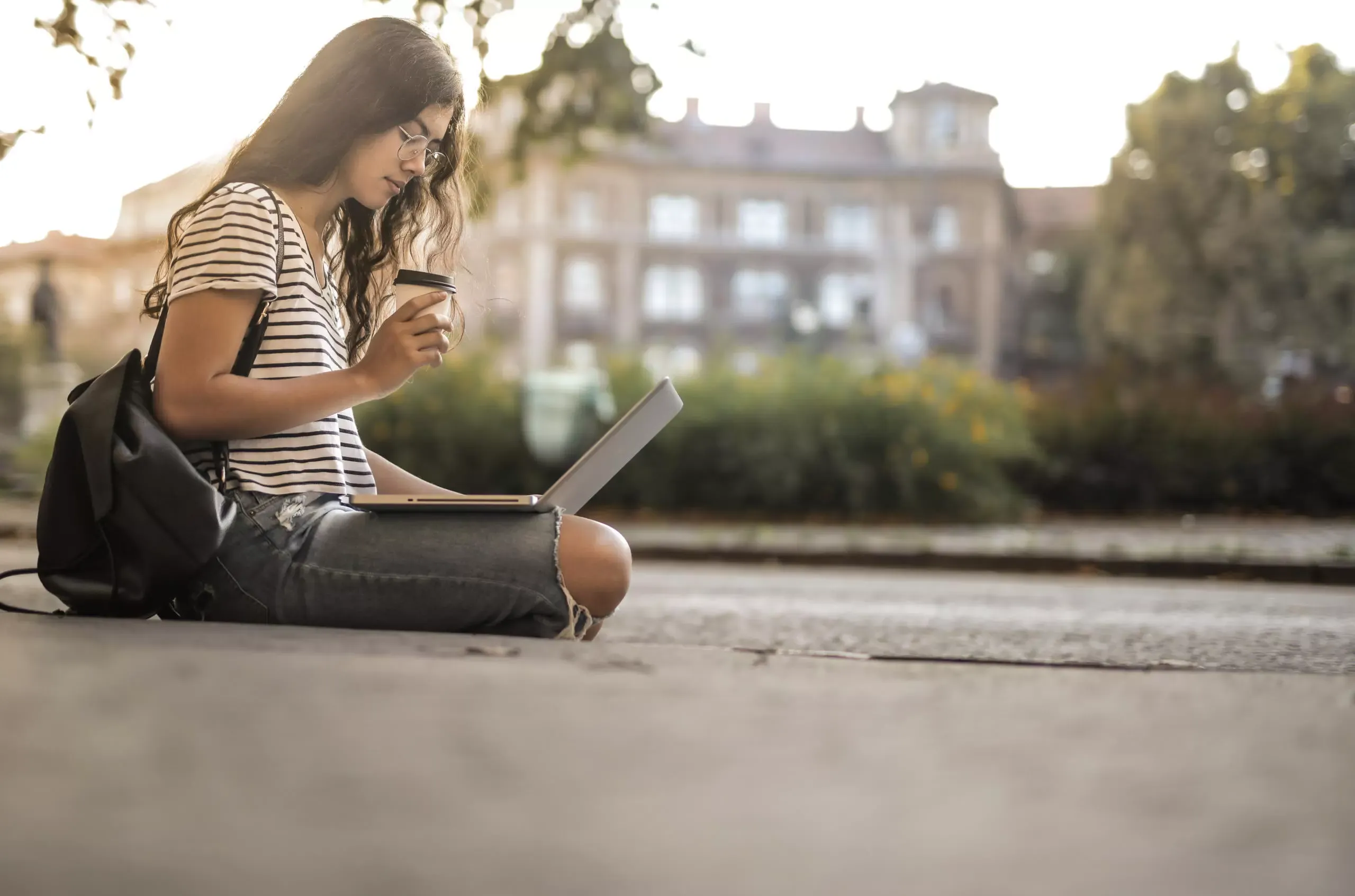 woman using laptop while drinking a coffee